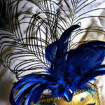 Decorative blue masquerade mask with peacock feathers and gold details.