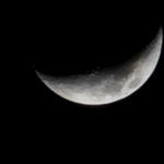 A crescent moon set against a deep black night sky.