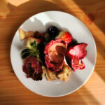 A plate of fruit peels and seeds illuminated by warm sunlight on a wooden table.