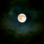Full moon glowing softly through a dark sky with subtle surrounding haze