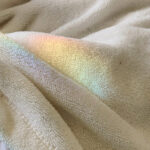 Rainbow light reflection appearing across soft textured fabric.