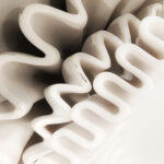 White decorative plate with layered folded edges in a sculptural pattern