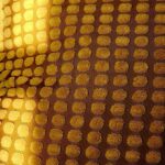 Warm light passing through a patterned surface creating a repeating grid of illuminated shapes