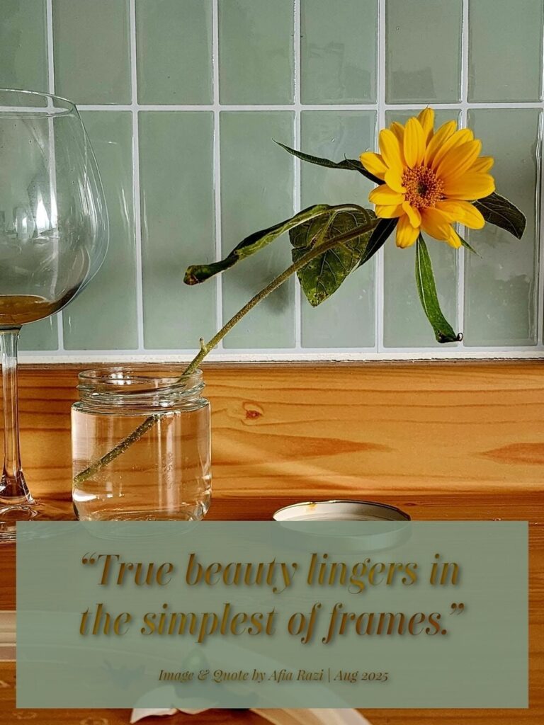 Yellow sunflower leaning from a glass jar, with the quote, “True beauty lingers in the simplest of frames.”